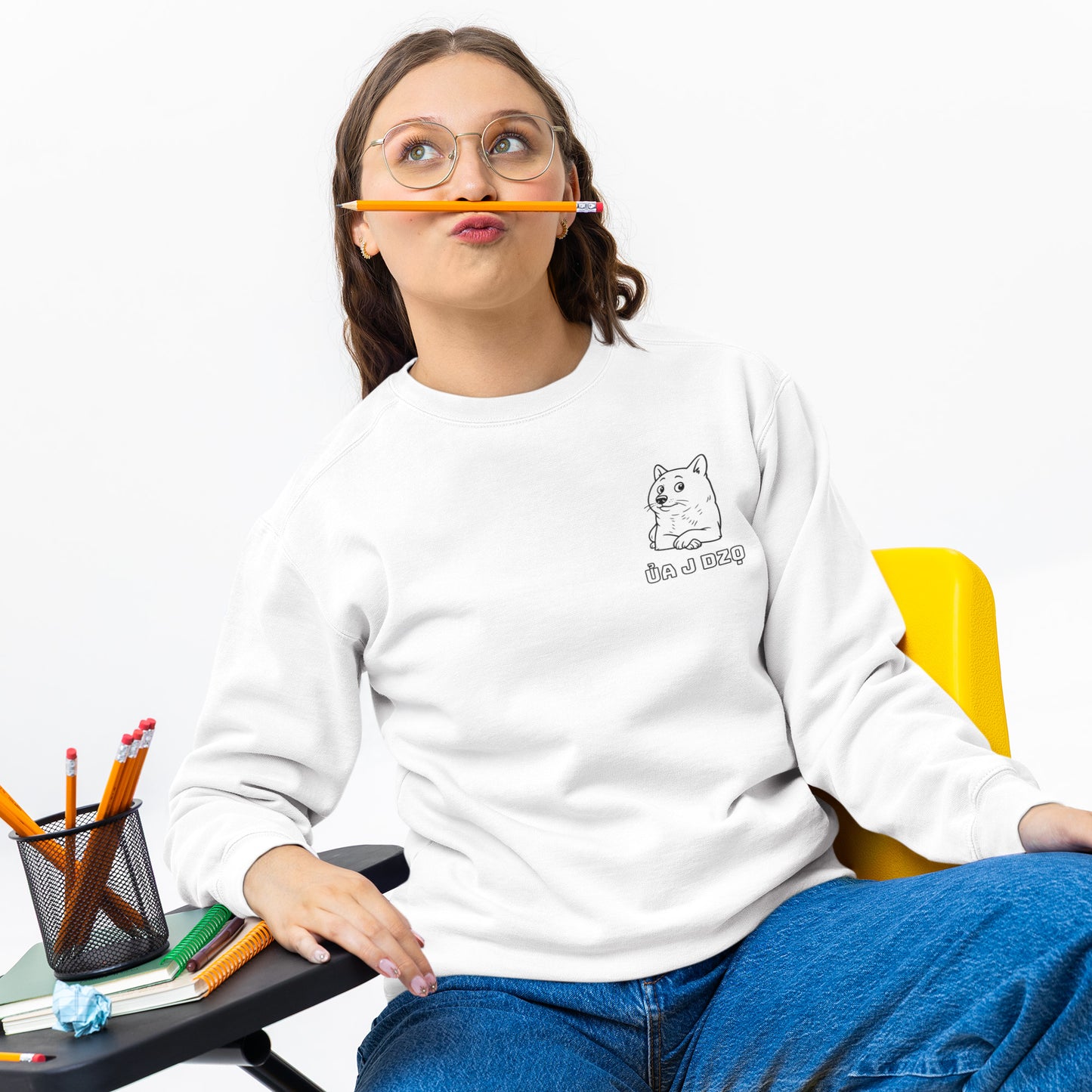 Young woman wearing a cozy white graphic crewneck sweatshirt with cute Shiba dog illustration, posing playfully with pencil and glasses in casual aesthetic streetwear for teens and young adults.