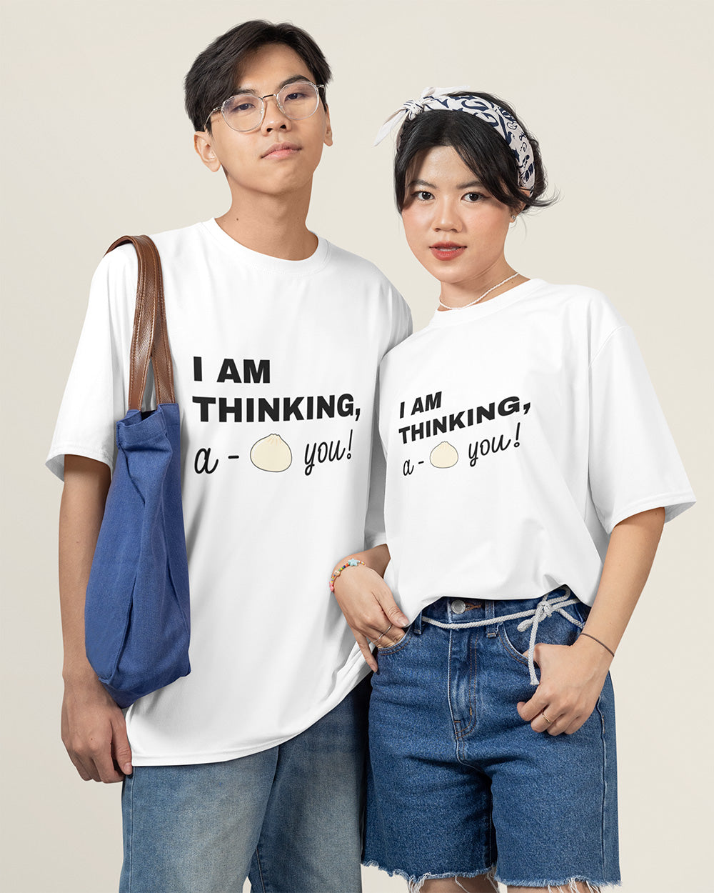 Couple wearing matching white “I Am Thinking, a Bao You!” graphic T-shirts from Vibe Thread Print. Cute matching outfit idea for couples who love playful, cozy, Asian-inspired fashion.