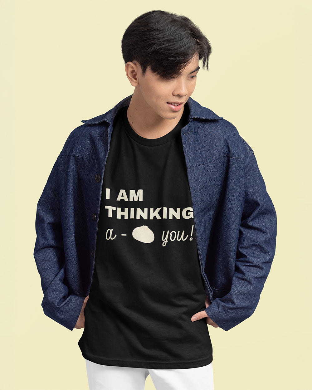 Male model wearing black bao bun graphic t-shirt styled with denim jacket for casual streetwear.
