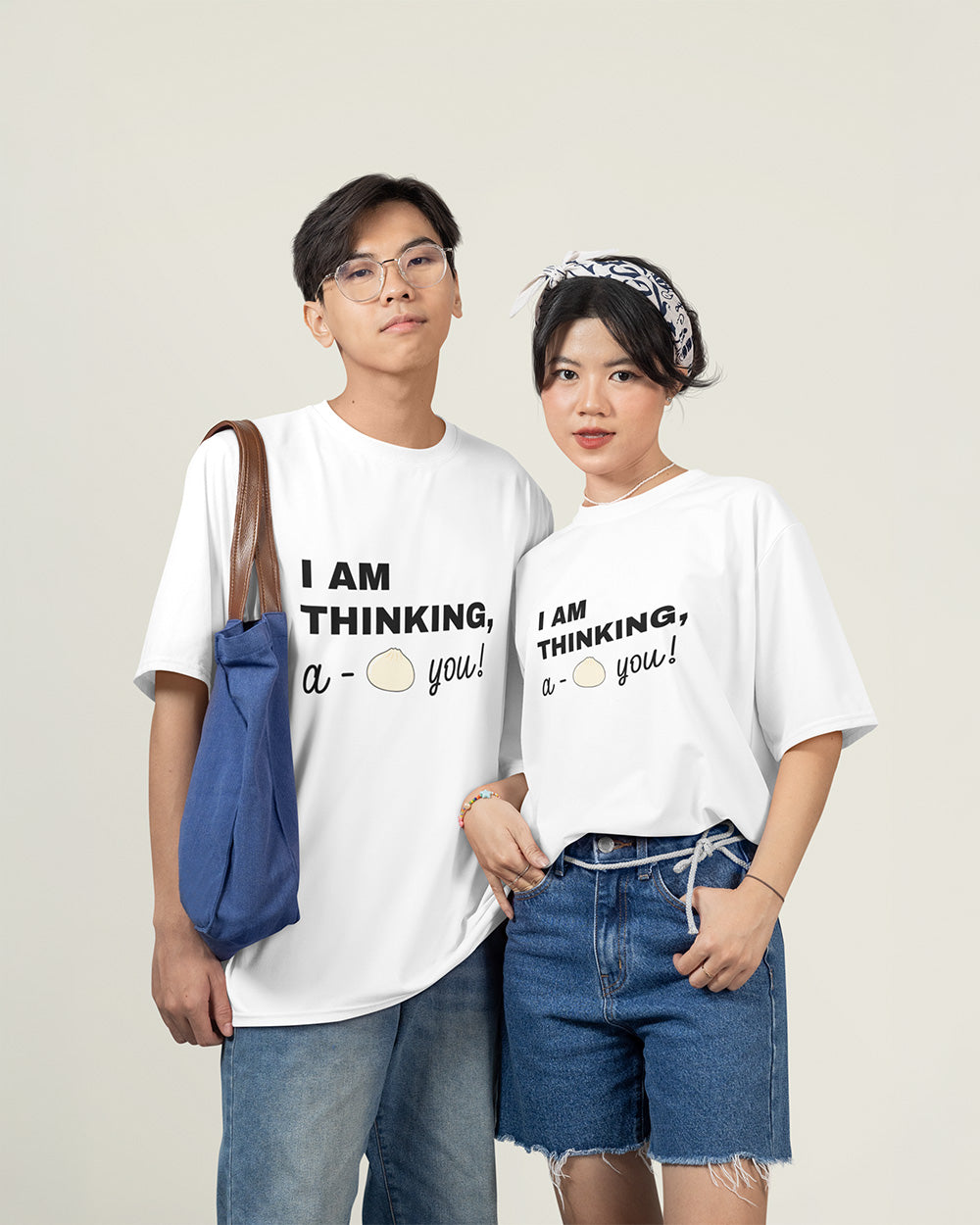 Male and female models wearing matching white cute bao bun graphic t-shirts with relaxed unisex fit style.