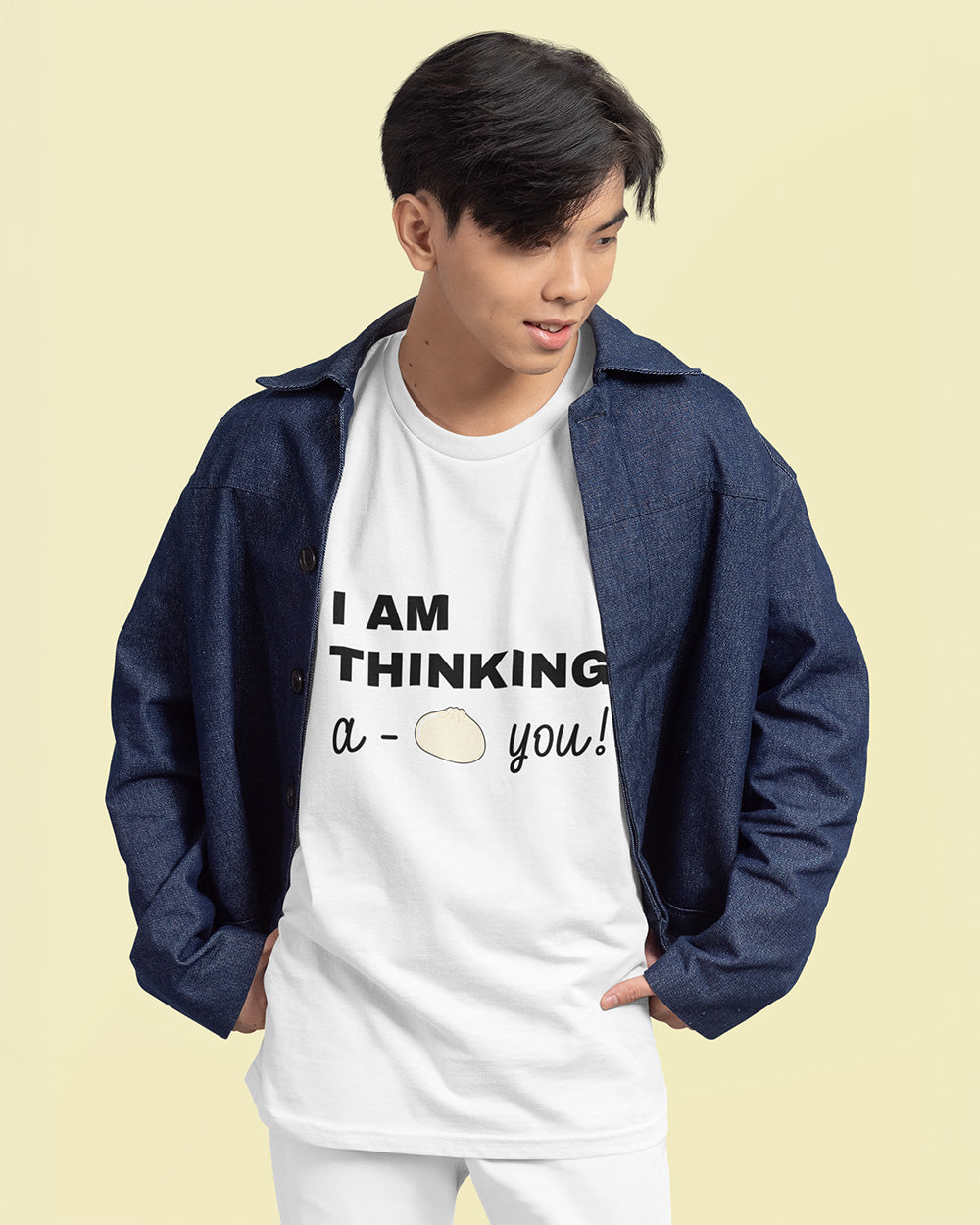 Male model wearing white bao bun graphic tee layered with denim jacket for trendy youth fashion.