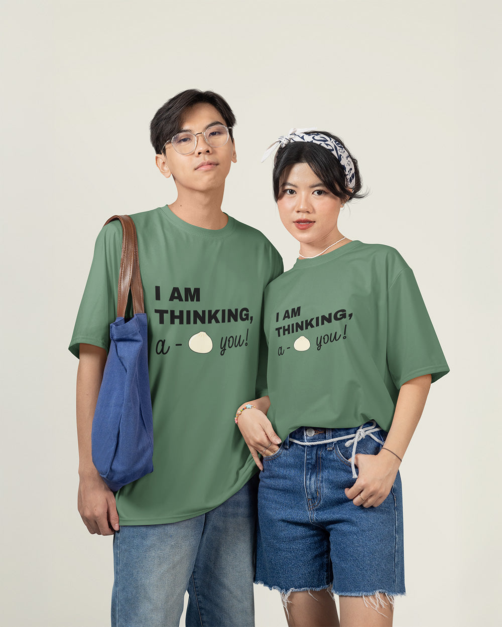 Male and female models wearing matching light green cute bao bun graphic t-shirts with relaxed unisex fit style.