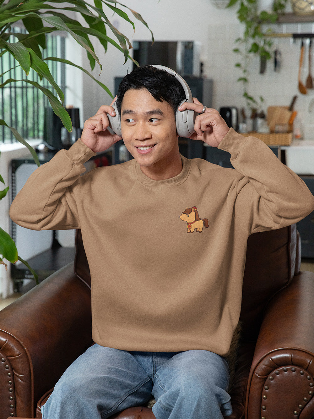 Trendy young adult wearing latte brown oversized crewneck sweatshirt with cute horse graphic, casual cozy aesthetic streetwear apparel.