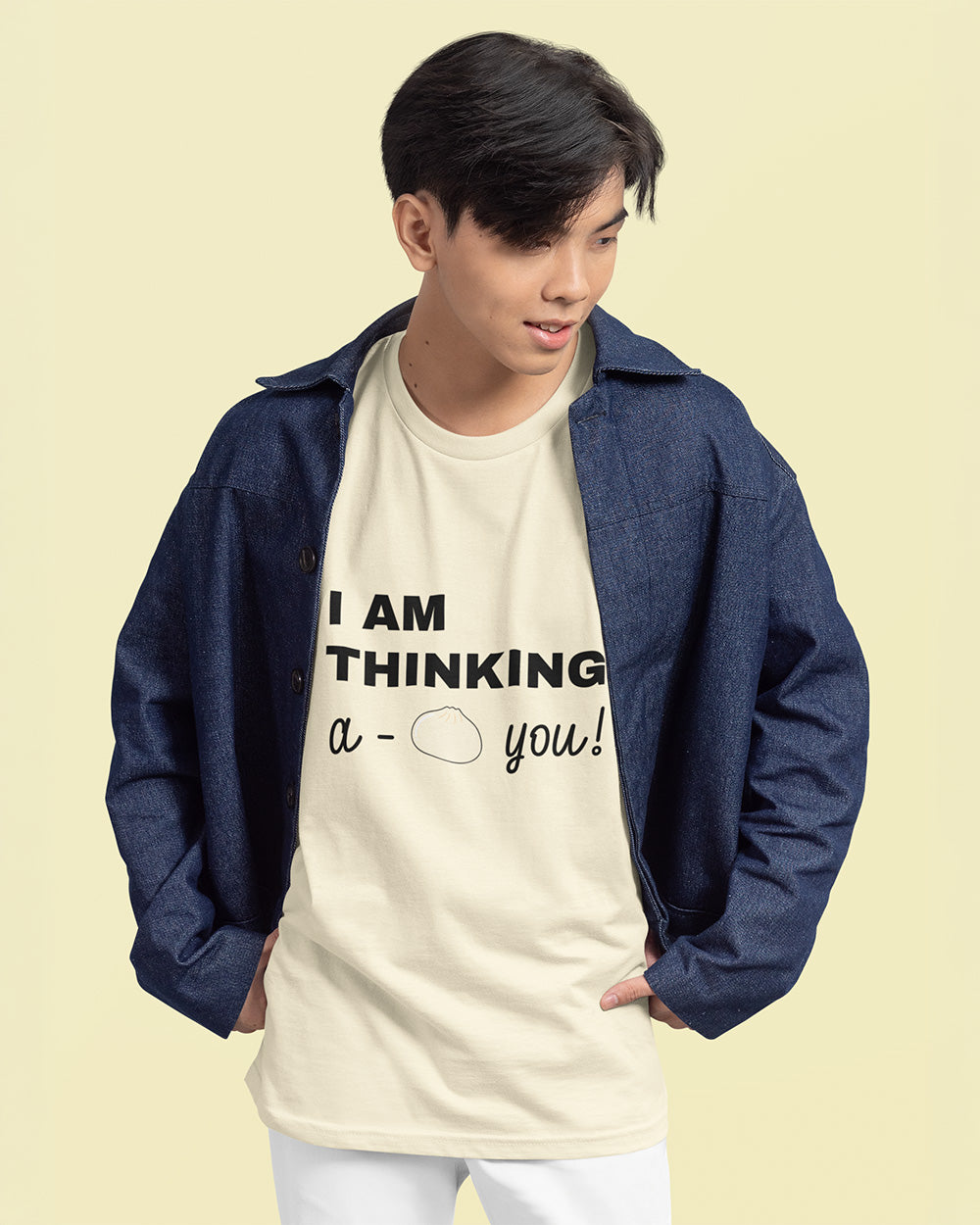Male model wearing ivory bao bun graphic tee layered with denim jacket for trendy youth fashion.
