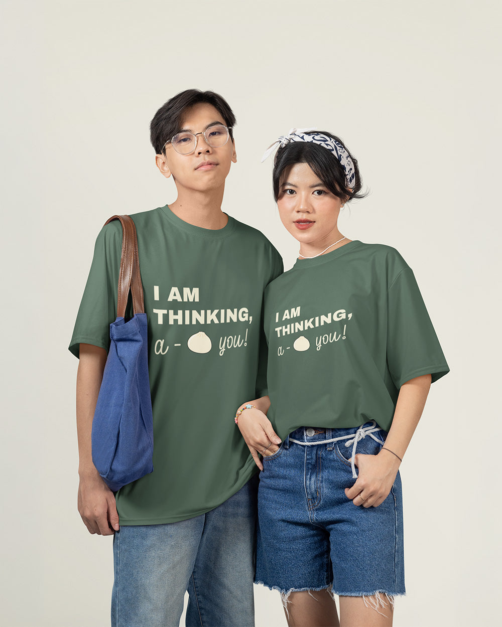Male and female models wearing matching blue spruce cute bao bun graphic t-shirts with relaxed unisex fit style.