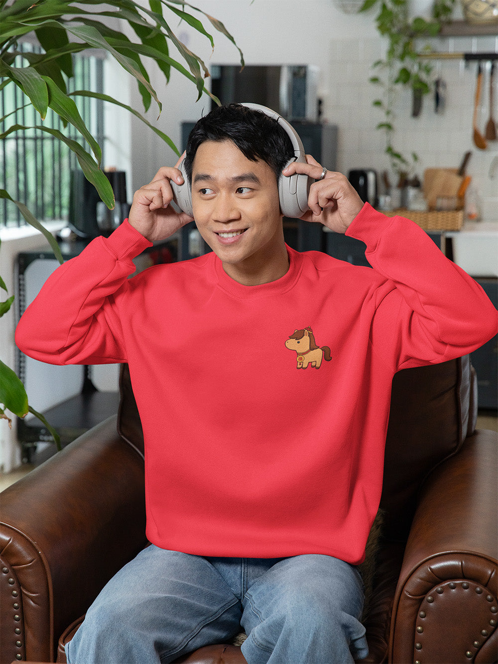 Smiling model wearing bright team red oversized crewneck sweatshirt with cute horse embroidery, playful kawaii streetwear fashion for youth.