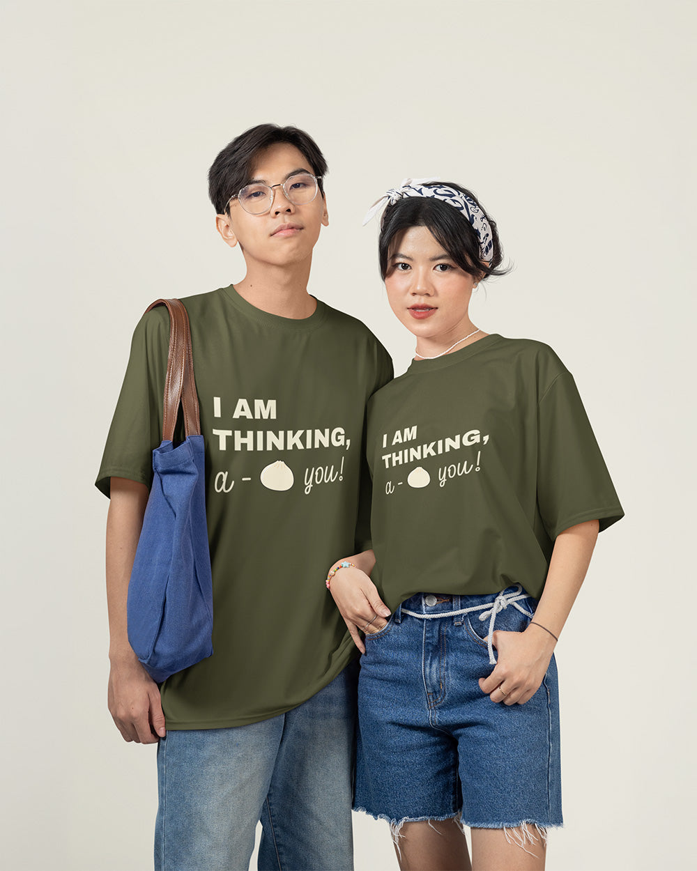 Male and female models wearing matching sage green cute bao bun graphic t-shirts with relaxed unisex fit style.
