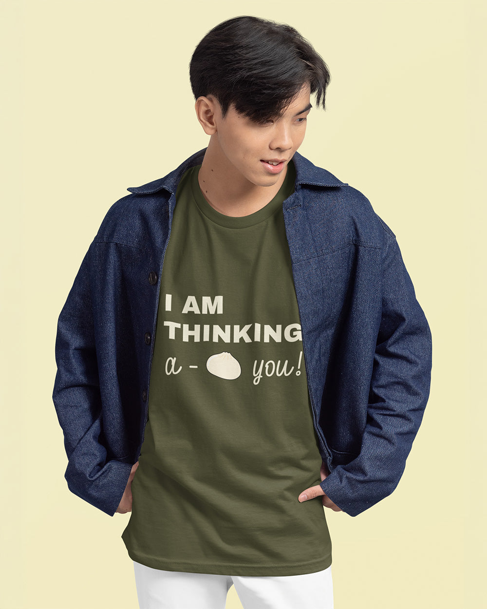 Male model wearing sage green bao bun graphic tee layered with denim jacket for trendy youth fashion.