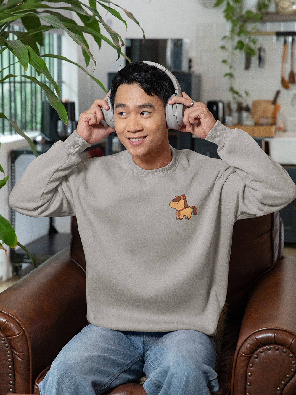 Young adult wearing carbon grey oversized crewneck sweatshirt with embroidered horse graphic, cozy minimalist streetwear aesthetic for teens.