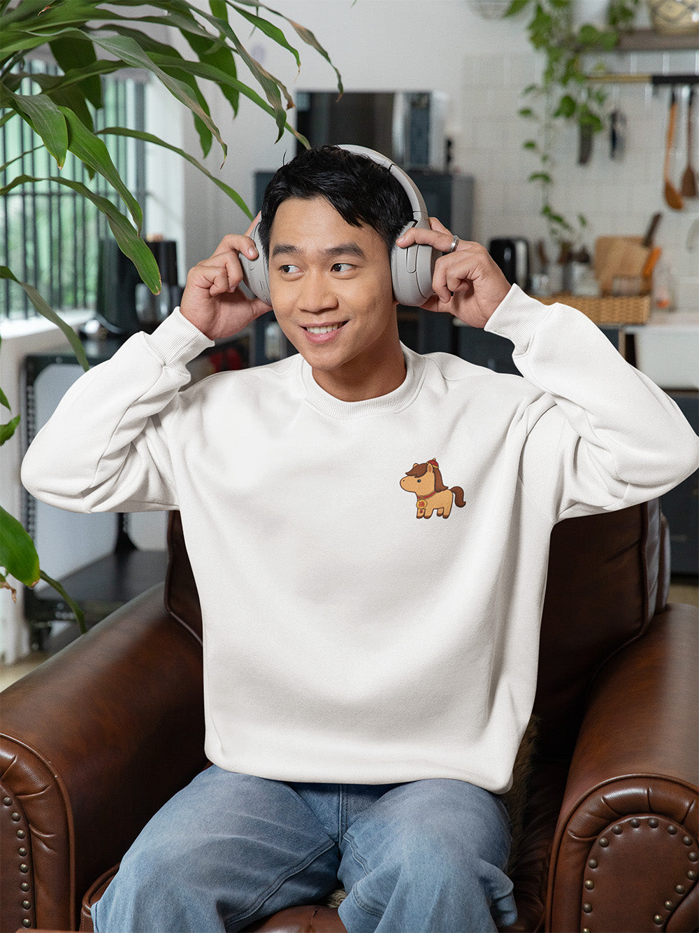Young man in white oversized crewneck sweatshirt with adorable horse embroidery, clean cozy streetwear look for teens and young adults.