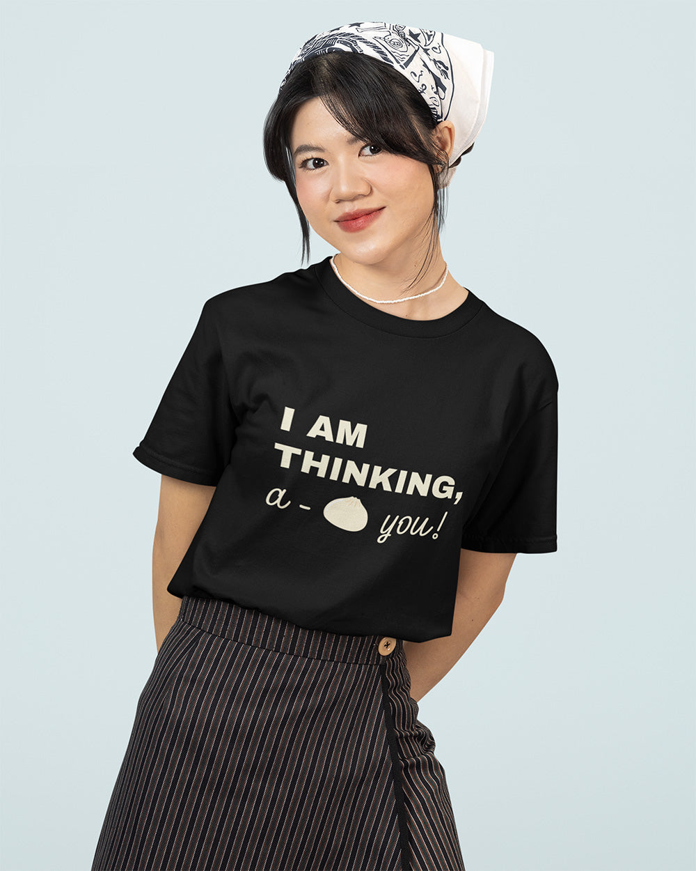 Trendy young woman wearing a black graphic tee with playful text ‘I am thinking, a-bao you!’ – cute pun design perfect for food lovers and casual streetwear fashion.