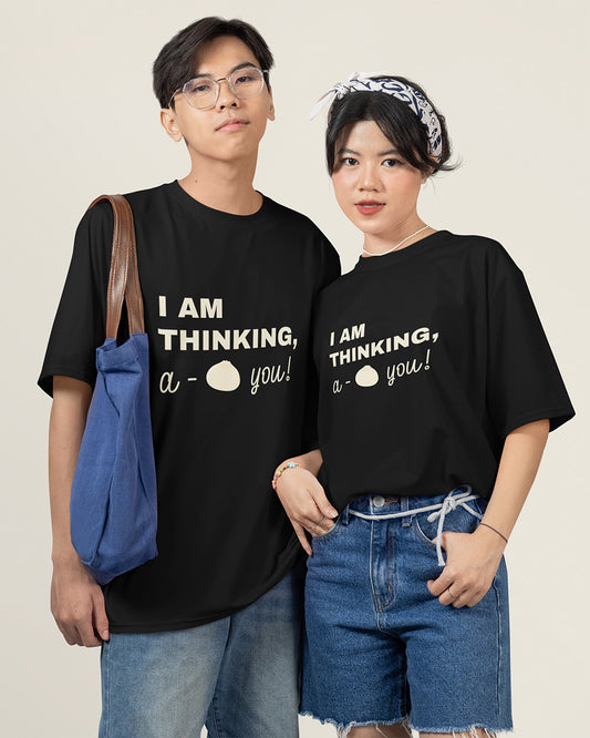 Trendy young couple wearing matching black graphic T-shirts with the playful text ‘I am thinking, a-bao you!’—a cute pun design perfect for couples, food lovers, and casual streetwear fashion. Ideal gift idea for teens and young adults who love fun and stylish matching outfits.