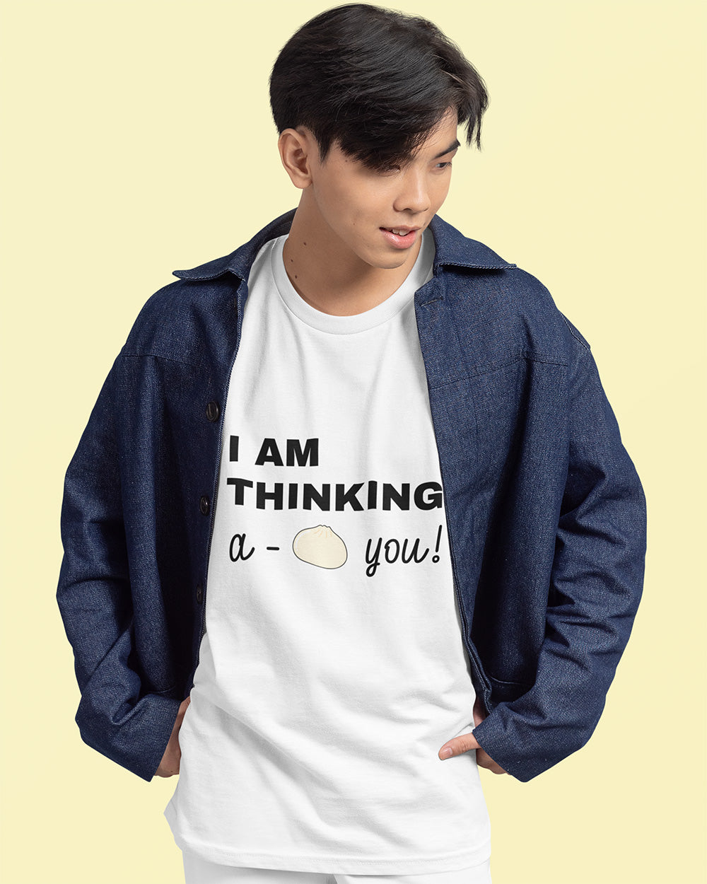 Male model styling white “I Am Thinking, a Bao You!” T-shirt with denim jacket for a casual, cute streetwear vibe. Designed by Vibe Thread Print for young adults who love simple, food-themed fashion.