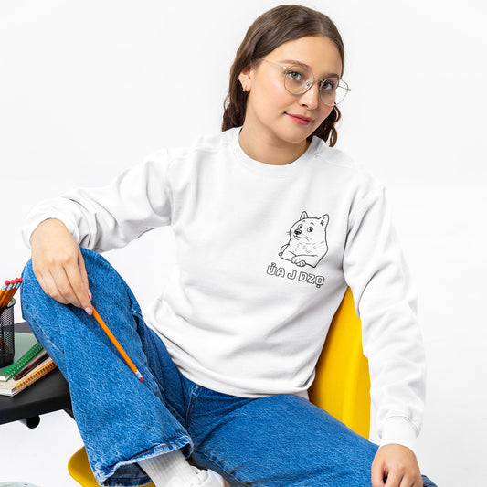A girl wearing a white sweatshirt with a graphic design, sitting on a chair.