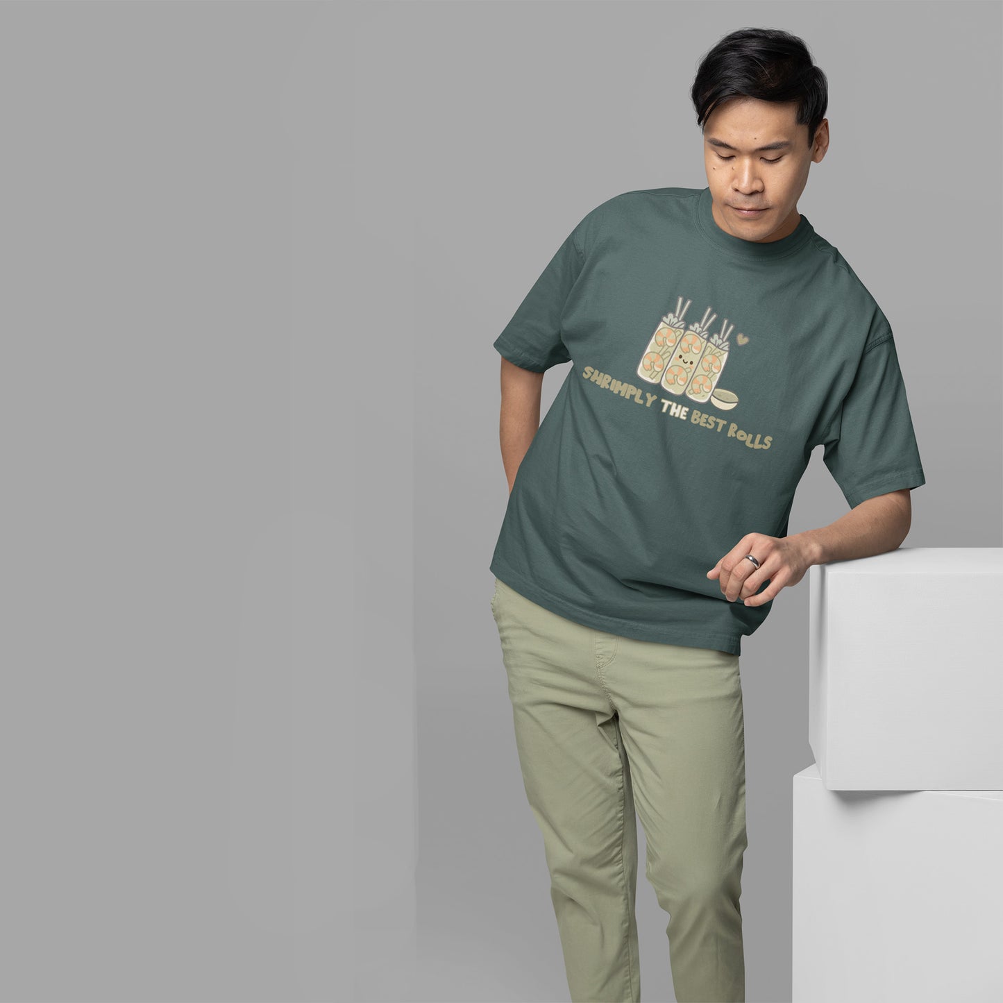 Man wearing a blue spruce t-shirt with text and graphics, standing against a gray background.